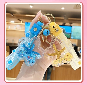 Detail of flower-shaped liquid starfish keychain with blue and yellow sand glitters