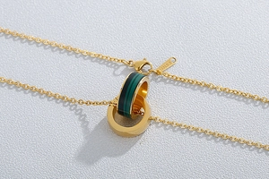 Close-up of golden stainless steel double-ring necklace with green striped texture detail