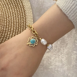 Detailed shot of golden chain bracelet with turquoise flower and baroque pearl accents
