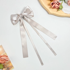 Detail of elegant champagne satin bow hair clip with long ribbons on white background
