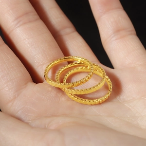 Macro shot of three gold titanium steel rings with textured fish scale patterns on palm