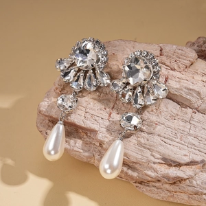 Detail of baroque silver earrings with drop pearls and sparkling crystals on wood