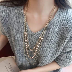 Close-up of elegant multi-layer gold chain necklace with faux champagne pearls on a sweater