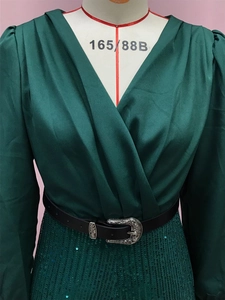 Detailed view of green V-neck satin bodice with sequined skirt and buckled waist belt
