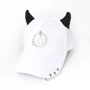 Detail of white baseball cap with black devil horns, metal star ring and brim piercings