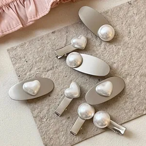 Detailed view of an 8-piece pearl hair clip set with heart and round charms on silver alloy