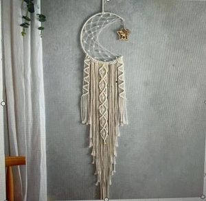 Detail of hand-woven moon and star dreamcatcher with macrame tassels in cream cotton