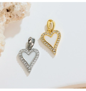 Close-up of gold and silver heart pendants with white inlay and sparkling stones