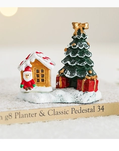 Close-up of miniature Christmas scene with Santa Claus, gold house, and snowy trees