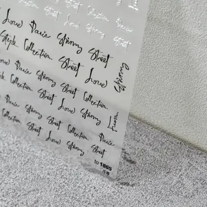 Close-up of 5D embossed nail stickers featuring black and silver artistic Paris lettering