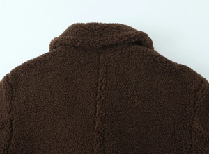 Detail of dark brown faux shearling coat showing collar seam and thick fleece texture