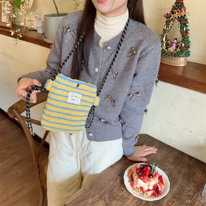 Detail of soft blue and yellow striped plush crossbody bag with woven letter label