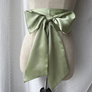 Gros plan d'une ceinture corset en satin vert sauge avec nœud sur un mannequin de mode