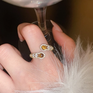 Detail of gold snake-style open ring with brown tiger eye stones and zircon accents