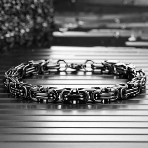 Macro shot of black stainless steel Byzantine chain links with polished metallic texture