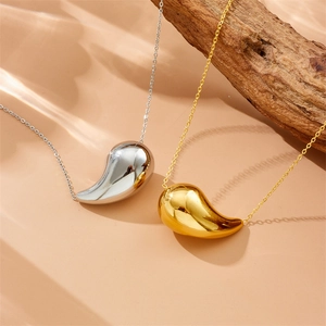Close-up of gold and silver hollow teardrop pendants on smooth metal necklaces