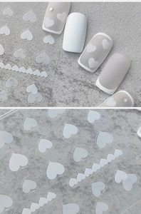 Macro detail of 5D heart nail art stickers with embossed white patterns and 3D textures