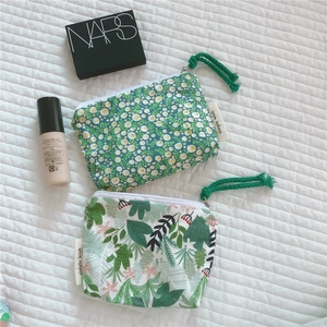 Flat lay of mini floral and leaf cotton pouches with zippers on white linen