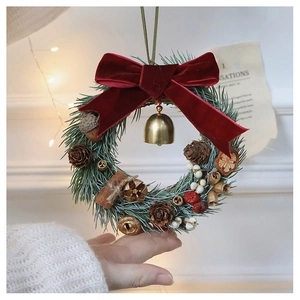 Detail of Christmas wreath featuring red velvet bow, golden bells and pine needles