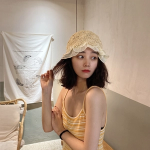 Detailed view of handmade crochet straw hat featuring delicate white lace ruffle edges