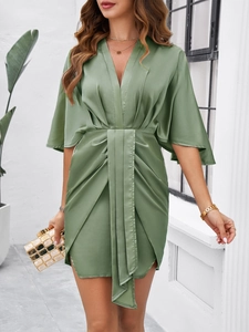 Detail view of a green satin V-neck mini dress with waist tie and pleated design