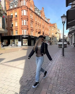Street style shot of navy cropped jacket paired with brown corset and denim pants