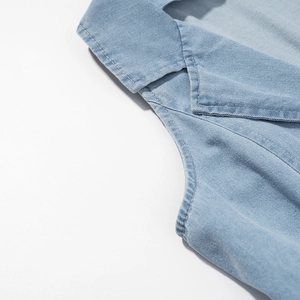 Detail van lichtblauwe denim jurk met reverskraag en versterkte dubbele stiksels