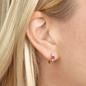Gold hoop earrings with red-purple gemstone and white diamonds on female model