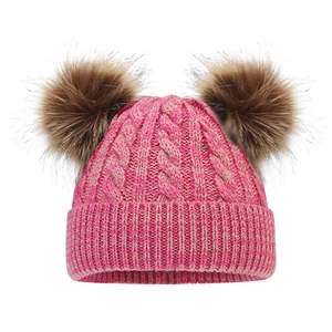 Close-up of pink knit winter hat with double brown faux fur pom-poms and cable texture