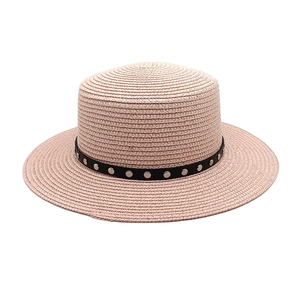 Gros plan sur un chapeau de paille rose avec ruban noir clouté et texture tressée