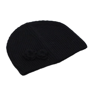 Detail of black ribbed knit beanie featuring a crochet flower ornament for winter warmth