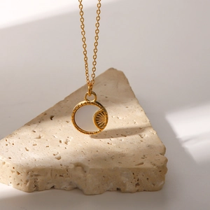 Close-up of golden sunburst pendant with shell inlay on minimalist beige stone base