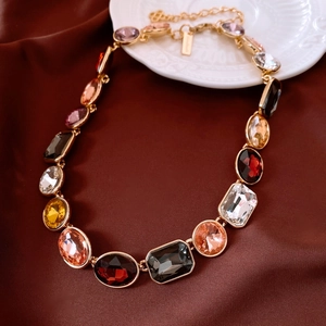 Macro shot of vintage gold necklace with multi-color oval and rectangle gemstones on silk