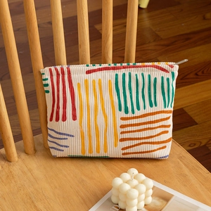 Detail of floral corduroy makeup bag showing colorful abstract stripes and soft texture