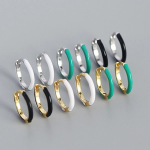 Detail of colorful enamel huggie hoop earrings in gold and silver finish