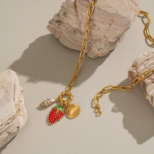 Dettaglio della collana in oro 18K con ciondoli a fragola, conchiglia e chiocciola su rocce