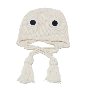 Detailed knit texture of a cream frog-style hat with cartoon eyes and long tassels