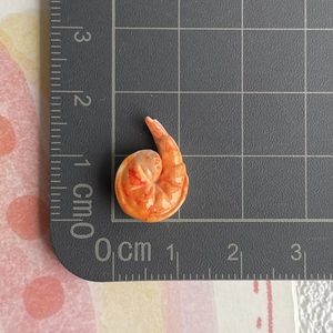 Miniatur-Garnele aus Harz, Detailansicht mit Größenangabe von 1,5 cm auf Skala