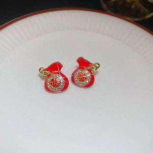 Macro view of festive red lucky bag stud earrings with gold trim and sparkly crystals