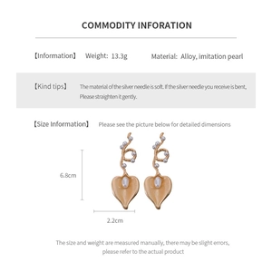 Detailed view of leaf-shaped gold drop earrings with white pearls and size measurements