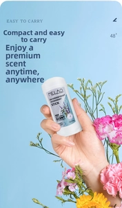 Close-up of MELAO 75g deodorant stick held by hand with fresh flowers on blue background