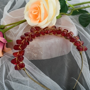 Close-up of handmade deep red crystals hand-wrapped with golden wire on a bridal crown