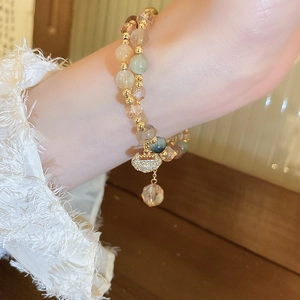 Close-up of double-layer beaded bracelet featuring a sparkling diamond-set lock pendant