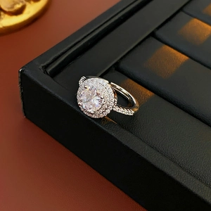 Detail of silver hollow zircon ring on a black leather jewelry display box with soft light