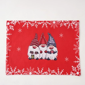 Close-up of red Christmas gnome placemat featuring festive snowflakes and linen texture