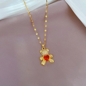 Detail of bear pendant with red heart and zircon stones on a gold chain necklace