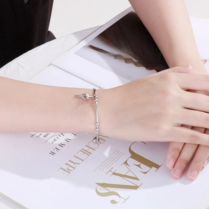 Detail of silver hollow star charm and small beads on minimalist steel chain bracelet