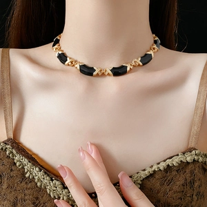 Close-up of vintage gold and black enamel interlocking necklace worn by a model