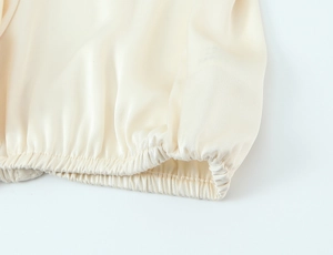 Detailed macro view of the silky beige fabric texture and elastic cuff stitching detail