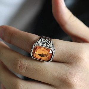 Macro shot of men's vintage silver ring with orange square gemstone and floral engraving